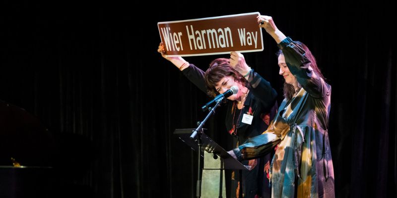 Two people hold up a sign reading Wier Harman Way