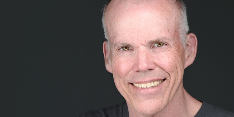 Headshot of Bill McKibben smiling (with fair skin, grey hair, and black t-shirt)