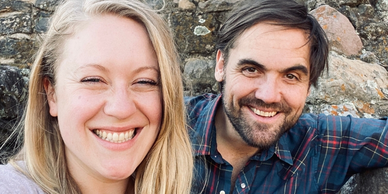 Kaylee (with long blonde hair) and Mikey (with short brown hair/beard) from Bug Friend pose and smile together.