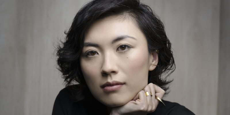 Headshot of C Pam Zhang (with fair skin and chin-length black hair) resting her chin on her palm.
