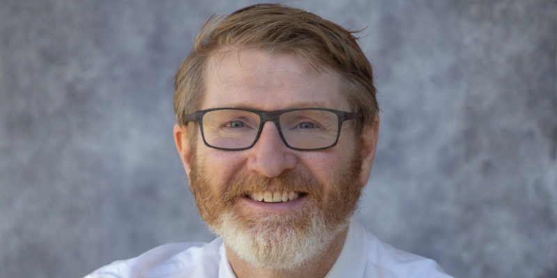 Headshot of Chuck Klosterman (with short blonde hair, beard, eyeglasses, and white button-down)