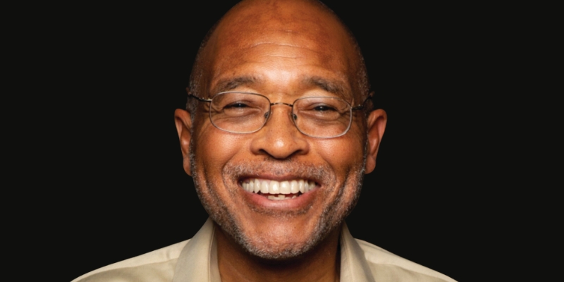 Headshot of Clyde W. Ford (bald, with brown skin, eyeglasses, and beige dress shirt)