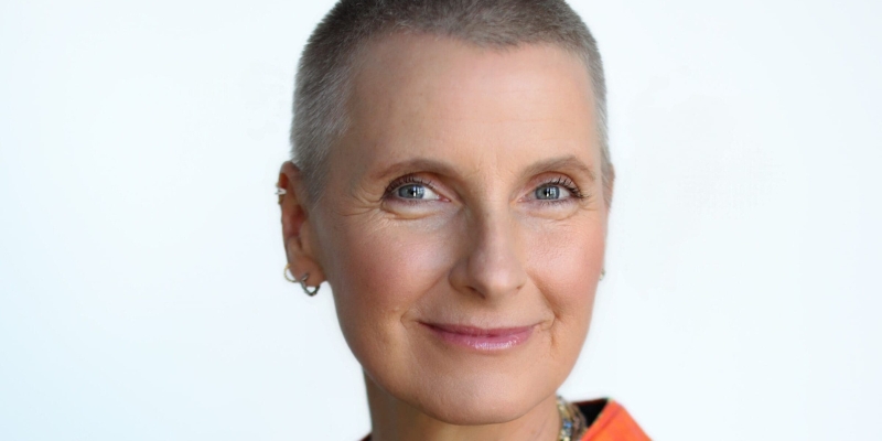 Headshot of Elizabeth Gilbert (with fair skin, blonde buzzcut, and small gold hoop earrings)