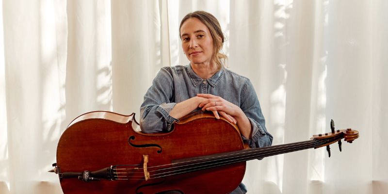Mikki Ulaszewski (with purple hair and eyeglasses) smiles and holds up one of their puppets.