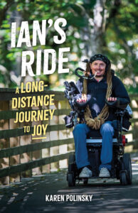 Book cover for "Ian's Ride: A Long-Distance Journey to Joy" by Karen Polinsky, featuring Ian Mackay sitting and smiling in an electric wheelchair, next to wooden railing on an outdoor walking trail.
