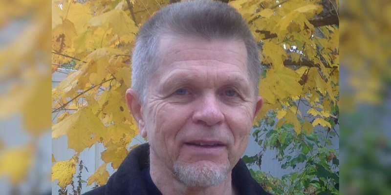 Headshot of James Janko (with fair skin and grey hair/beard, wearing a black jacket)