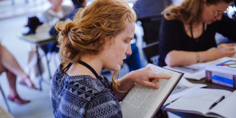 Maia Brown (with fair skin and long ginger hair) reads the Talmud.