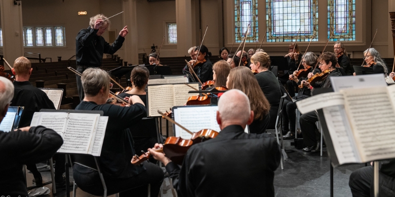 Thalia Symphony Orchestra performs on the Great Hall stage, led by a conductor. All performers are dressed in black.