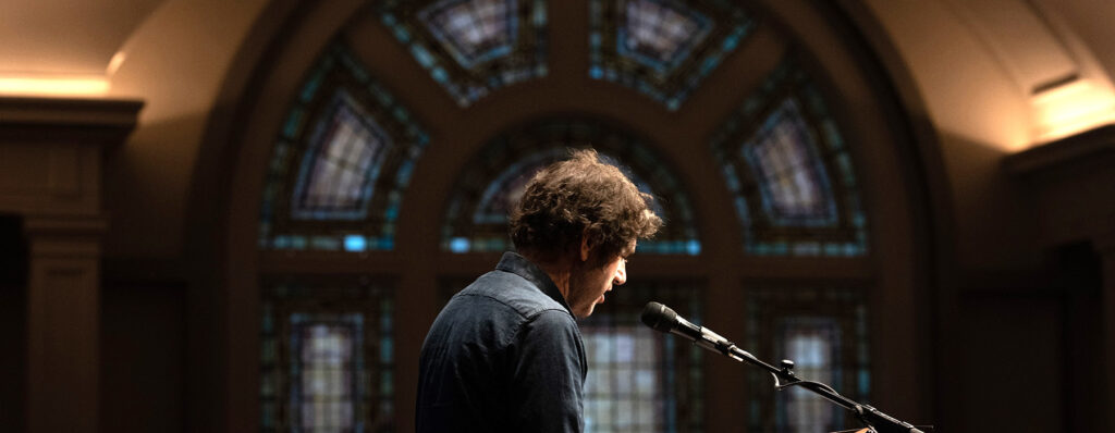 Wier Harman speaks into a mic in The Great Hall.