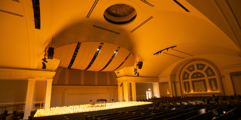 The Great Hall stage with 4 chairs surrounded by lit candles.