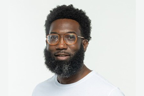 Shamichael Hallman wearing a white tee with bicycles and orange glasses